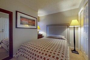 Un dormitorio con una cama, una mesita de noche, una lámpara y un cuadro en la pared.