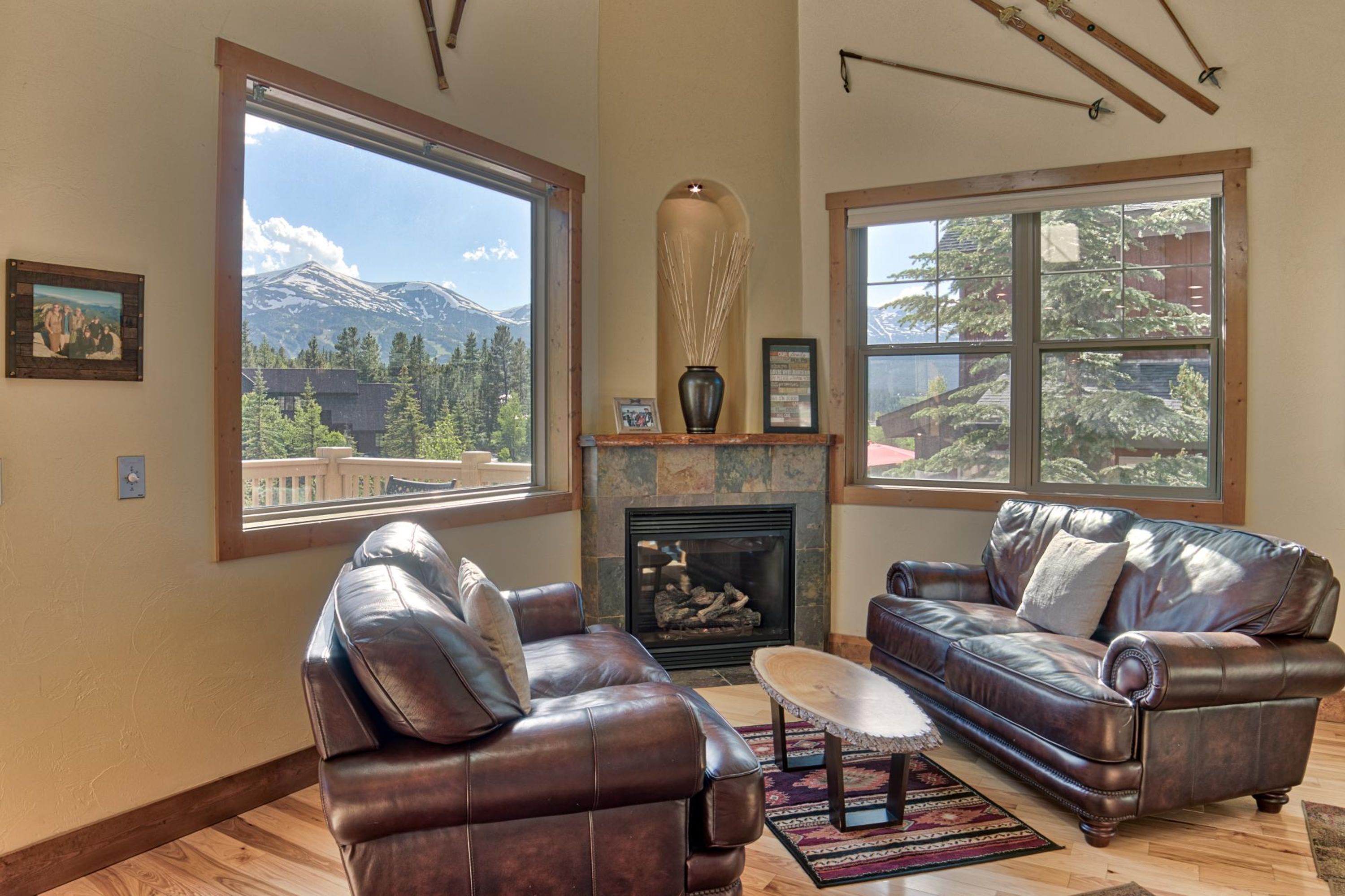 A living room with leather sofas, a fireplace, and large windows with mountain views.