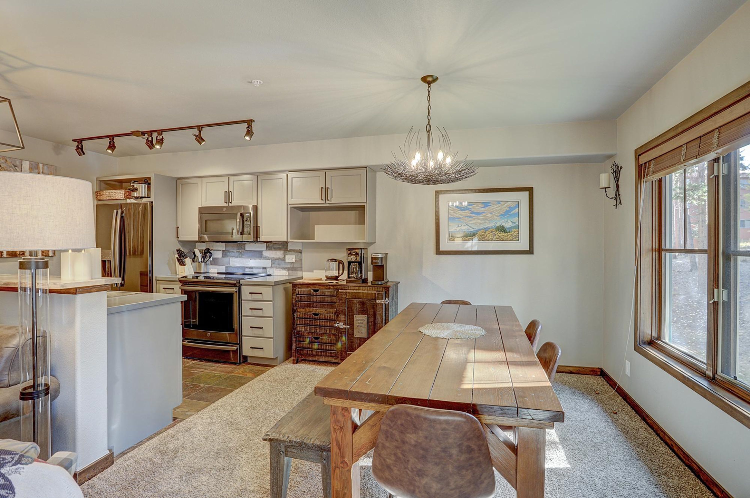 A kitchen with a dining table, cabinets, and a chandelier.