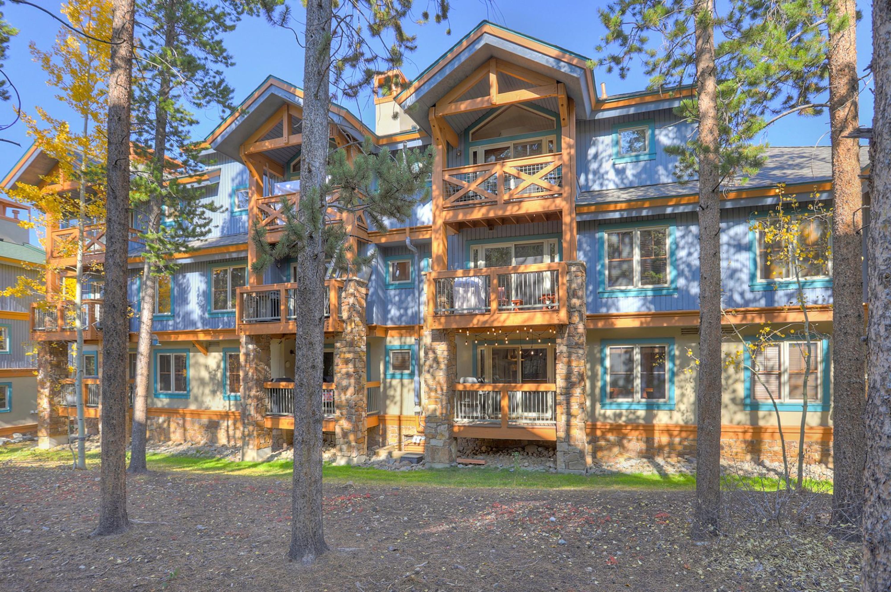 A multi-story lodge with balconies and a stone facade, surrounded by trees.