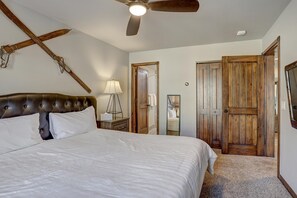 Ein Schlafzimmer mit einem großen Bett, einem Deckenventilator, Holztüren und einem Spiegel.