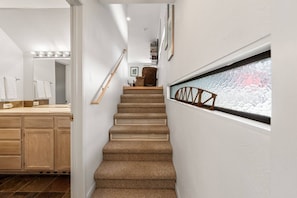 A staircase leading to a bedroom with a window, a wooden chair, and a shelf with books. - New Listing! Budget Friendly, Prime Location, Private Deck (Telluride)