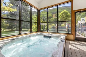 A hot tub with a view of a forested landscape through large windows. - New Listing! Budget Friendly, Prime Location, Private Deck (Telluride)