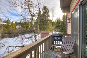A deck with a grill, chairs, and a view of a snowy landscape. - Liftside Retreat in Breckenridge (Breckenridge)