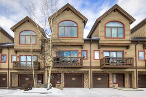 A multi-story residential building with a stone facade, multiple garage doors, and balconies. - Liftside Retreat in Breckenridge (Breckenridge)
