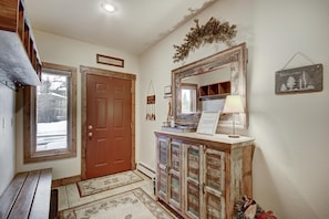 A hallway with a wooden door, a mirror, a welcome sign, and a cabinet with a lamp. - Liftside Retreat in Breckenridge (Breckenridge)
