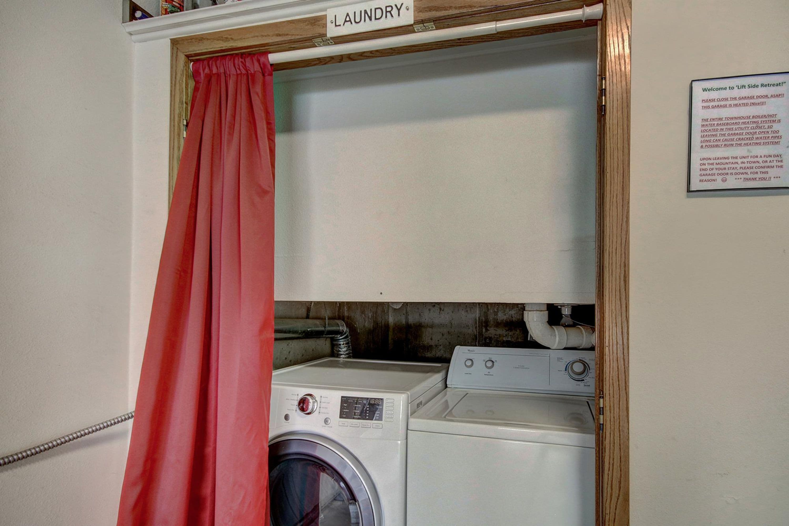 Ein Waschbereich mit einem Schild, das den Bereich als 'Laundry' kennzeichnet, einem roten Vorhang und einem Hinweis zum Garagentor.