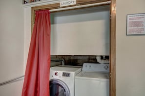 A laundry area with a sign indicating it is the 'Laundry' section, a red curtain, and a note about the garage door. - Liftside Retreat in Breckenridge (Breckenridge)