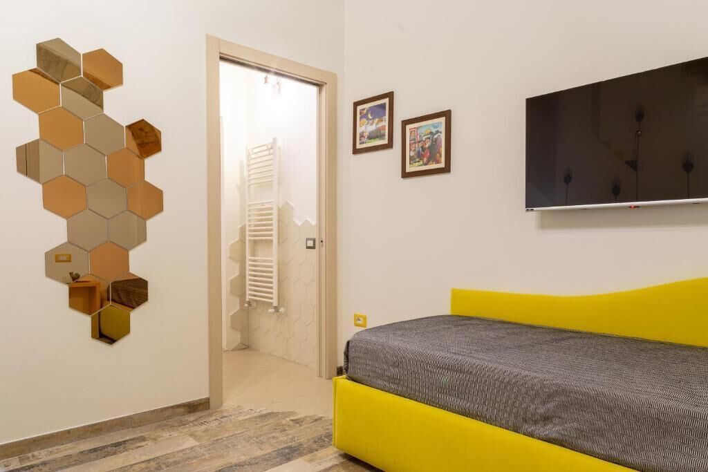 Una camera con un letto, una televisione a muro e un'apertura che conduce al bagno.