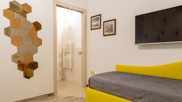Una camera con un letto, una televisione a muro e un'apertura che conduce al bagno.