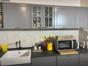 Uma cozinha com armários cinzas, micro-ondas, torradeira e pia.