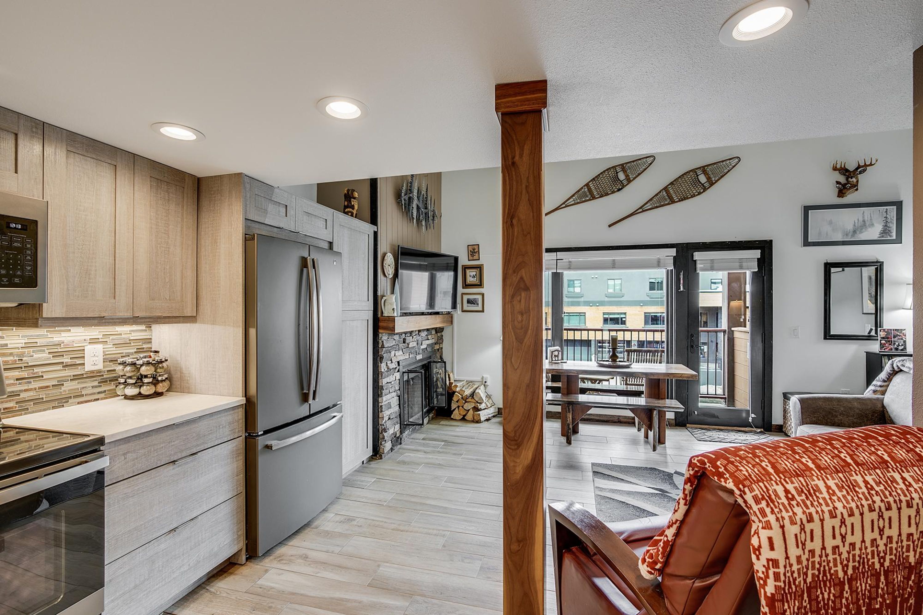 A modern kitchen with a built-in refrigerator, a stone fireplace, and a dining area with a bench.