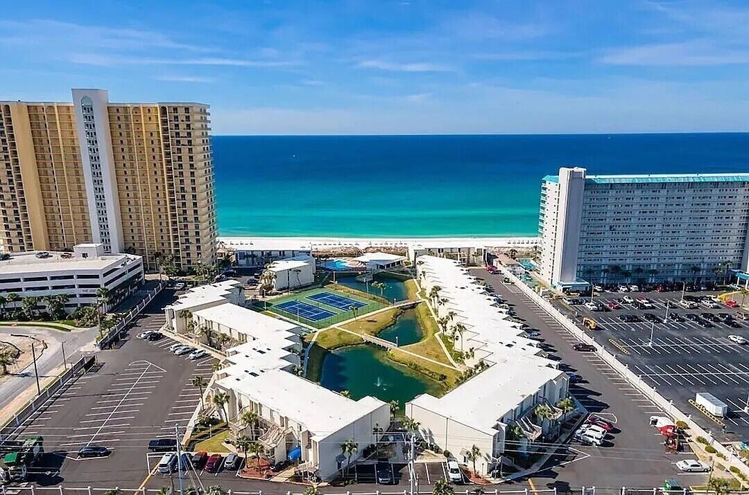 A hotel complex with multiple high-rise buildings, a parking area, and a pool.