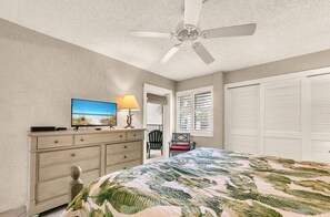 A bedroom with a bed, a ceiling fan, a television on a dresser, a window with blinds, and a chair. - BEACHFRONT COMPLEX, 2nd-Floor, park next to unit, steps to pool/wide open beach (Panama City Beach)