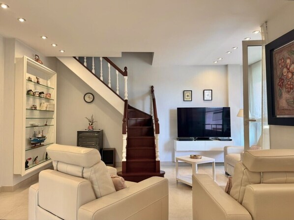 Ein modernes Wohnzimmer mit Treppe, Fernseher und Bücherregal.
