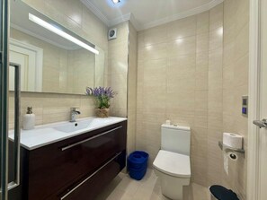 Ein modernes Badezimmer mit einem weißen Waschbecken, einem dunklen Waschtisch und einer weißen Toilette.