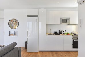A modern kitchen with white cabinetry, a built-in microwave, and a refrigerator. - Maranuelas 308 by VillaGranCanaria (Arguineguin)