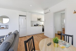 Eine moderne Wohnung mit Küchenzeile, einem Essbereich mit Tisch und Stühlen sowie einem Wohnzimmer mit Sofa.