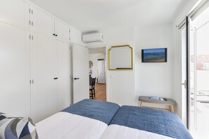 A bedroom with a bed, wardrobe, TV, and a view of the outside.