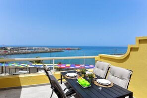 A balcony with a table set for dining, overlooking a marina with boats and a clear blue sky. - Maranuelas 308 by VillaGranCanaria (Arguineguin)