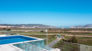 Ein Pool mit freiem Blick auf die Küste und die entfernten Hügel.