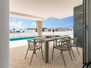 Eine Außenpatio mit Pool, einem Tisch mit Stühlen und Blick auf Gebäude im Hintergrund.