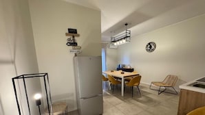 Eine moderne Küche mit Kühlschrank, Esstisch, Stühlen und einer Hängelampe.