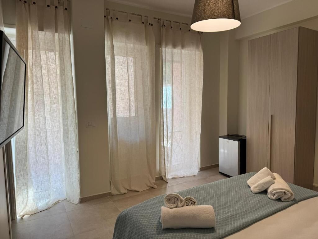 Ein Hotelzimmer mit Bett, Vorhängen, Schreibtisch und Lampe.