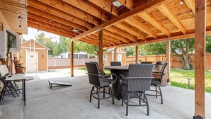 An outdoor patio with a wooden pergola, a dining table, and wicker chairs. - Spacious 4-bedroom house in welcoming Thornton, Cozy for families to relax. (Thornton)