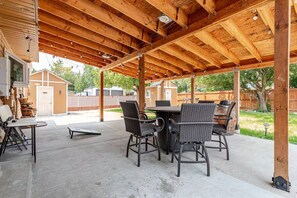 Eine Terrasse im Freien mit einer Holz-Pergola, einem Esstisch und Korbstühlen.