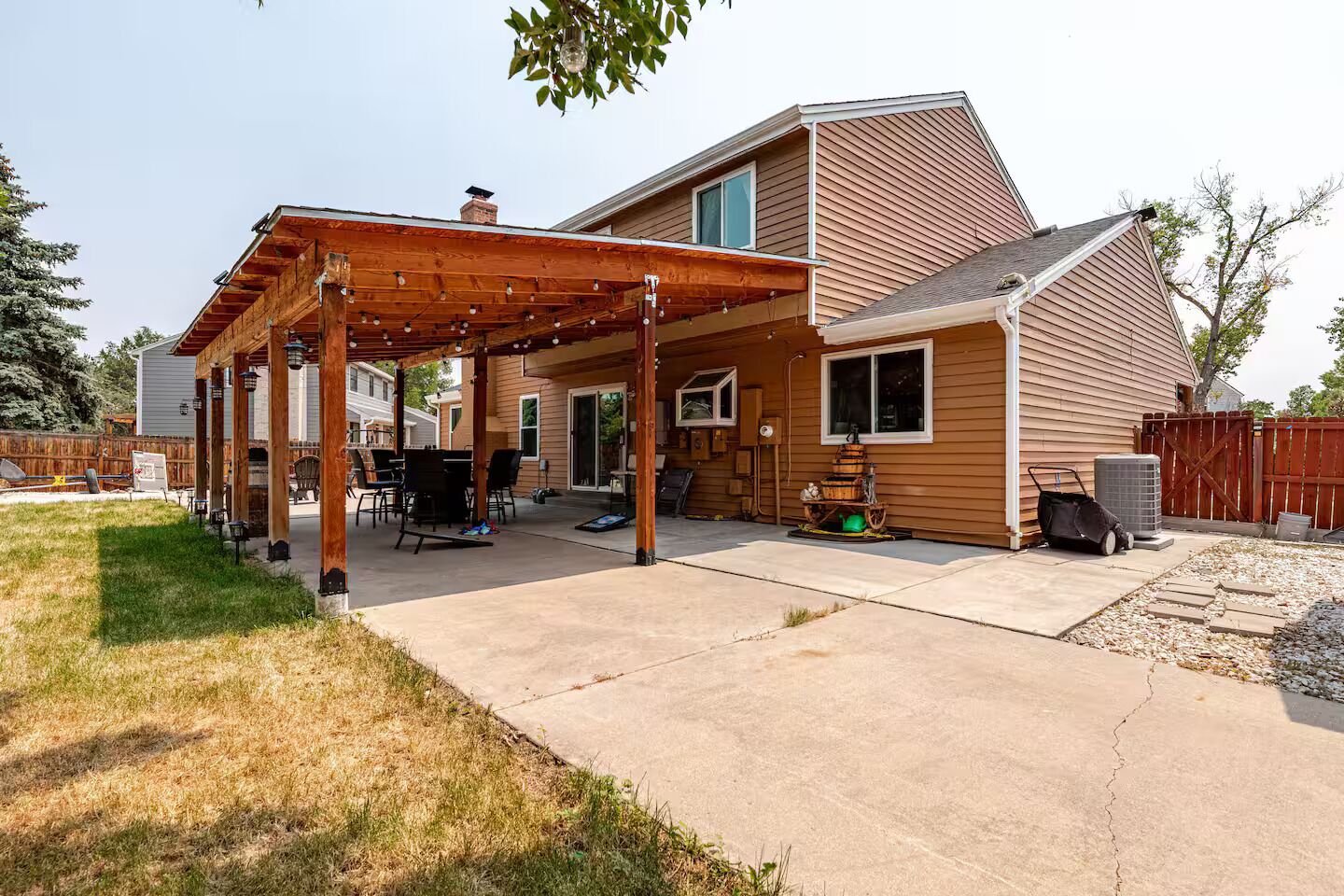 Une maison d’habitation dotée d’un patio couvert, d’une cheminée visible et d’une cour arrière clôturée.