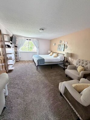 A bedroom with a bed, a sofa, a TV, and a window with curtains. - Spacious 4-bedroom house in welcoming Thornton, Cozy for families to relax. (Thornton)