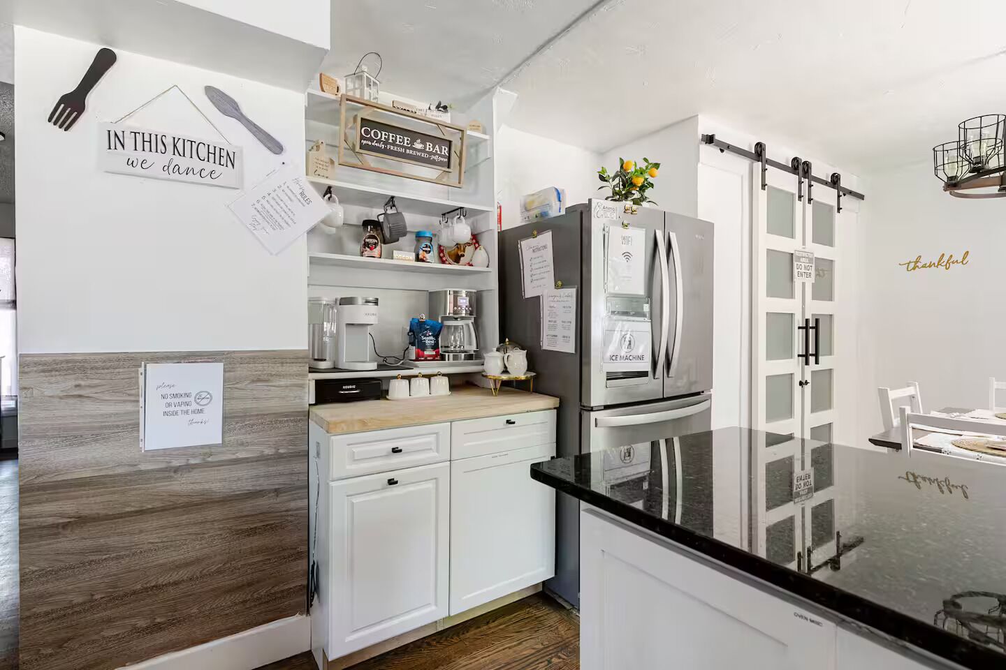 A modern kitchen with white cabinetry, a black countertop, and a refrigerator with a WiFi symbol.