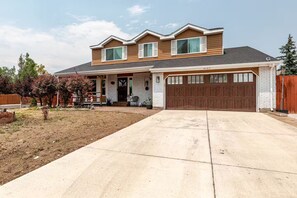 A two-story house with a front garage, a covered porch, and a landscaped yard. - Spacious 4-bedroom house in welcoming Thornton, Cozy for families to relax. (Thornton)