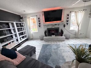 A living room with a fireplace, a flat-screen TV, and a bookshelf. - Spacious 4-bedroom house in welcoming Thornton, Cozy for families to relax. (Thornton)