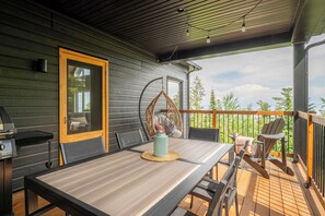 A wooden deck with a table and chairs, a hanging chair, and a grill. - Shack Saison - St-Lauwrence River (Petite-Rivière-Saint-François)