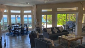 Uma sala de estar ampla com vista para o oceano, um conjunto de jantar e um sofá.