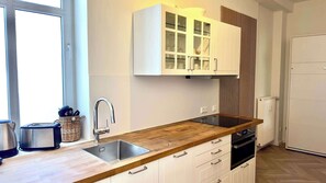 Une cuisine moderne avec un plan de travail en bois, un évier en acier inoxydable et des meubles de cuisine blancs.