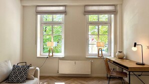 A room with two windows, a radiator, a desk with a chair, and a lamp. - Warnemünder Auszeit 2 (Rostock)