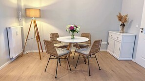A room with a round table, six wicker chairs, a floor lamp, a radiator, and a cabinet. - Warnemünder Auszeit 1 (Rostock)