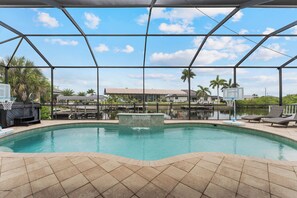 An indoor swimming pool with a clear view of the surrounding area, including a dock and palm trees. - Blue Tide Waterfront Pool & Hot Tub 2 En Suites (Cape Coral)