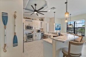 A modern kitchen with white cabinets, a central island, and pendant lighting. - Blue Tide Waterfront Pool & Hot Tub 2 En Suites (Cape Coral)