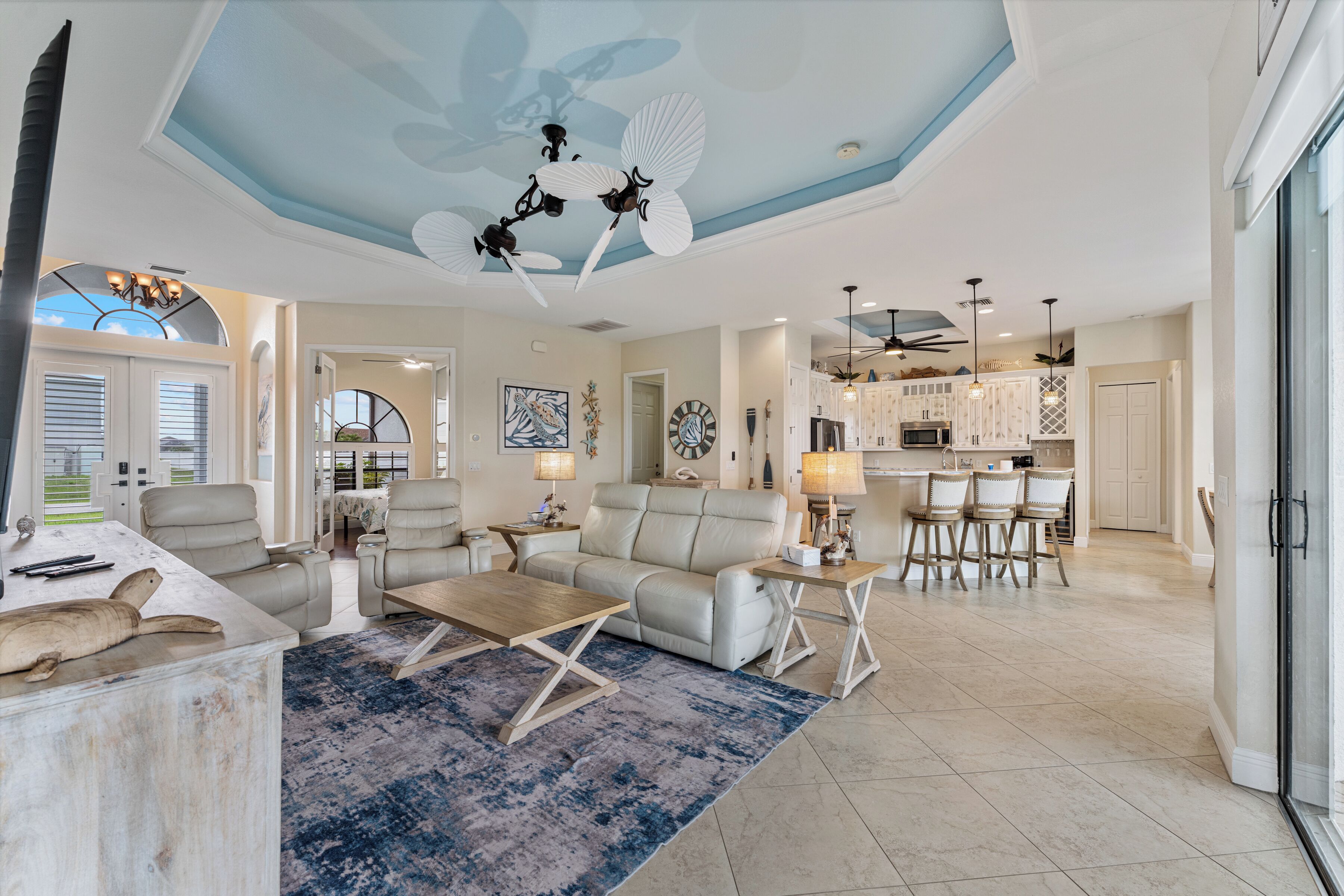 A spacious living area with a ceiling fan, a dining table, and a kitchen in the background.