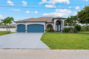 A two-story house with a garage, a driveway, and a well-maintained lawn. - Blue Tide Waterfront Pool & Hot Tub 2 En Suites (Cape Coral)