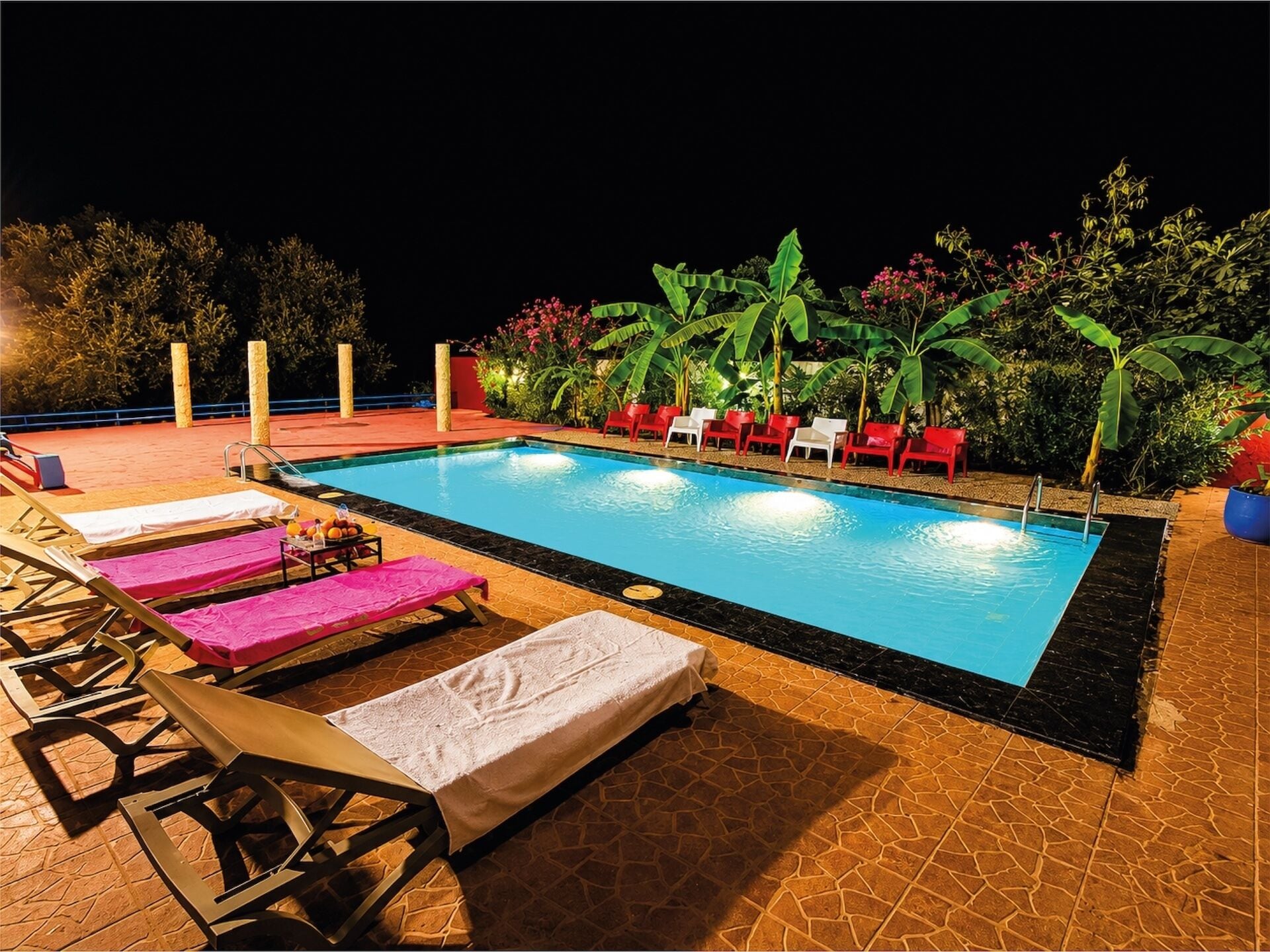 Une piscine avec des chaises longues et une terrasse carrelée.