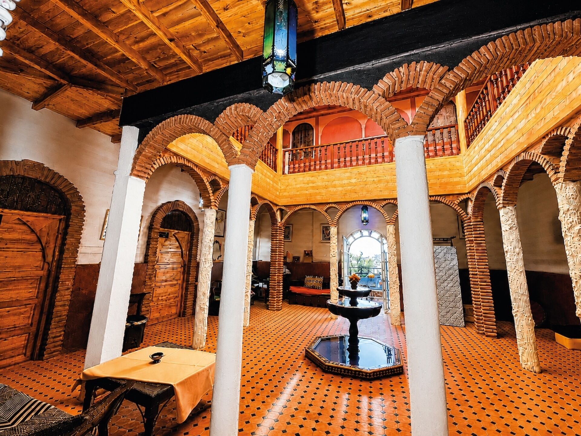 A spacious interior with wooden beams, arched ceilings, and a central fountain.