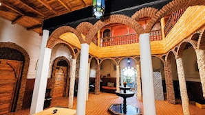 A spacious interior with wooden beams, arched ceilings, and a central fountain.