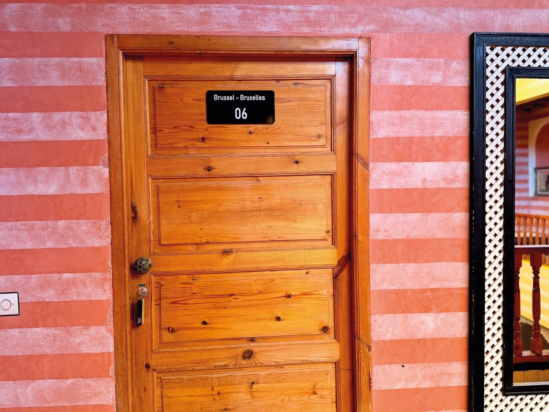 Puerta de madera con un cartel que indica el número de habitación 06, una cerradura y un candado.
