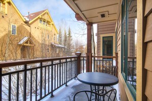 A balcony with a table and chairs, a railing, and a view of buildings and trees. - Waterhouse #5109 in Columbine Rd (Columbine Rd)