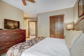 A bedroom with a bed, dresser, television, and a door leading to a bathroom. - Waterhouse #5109 in Columbine Rd (Columbine Rd)